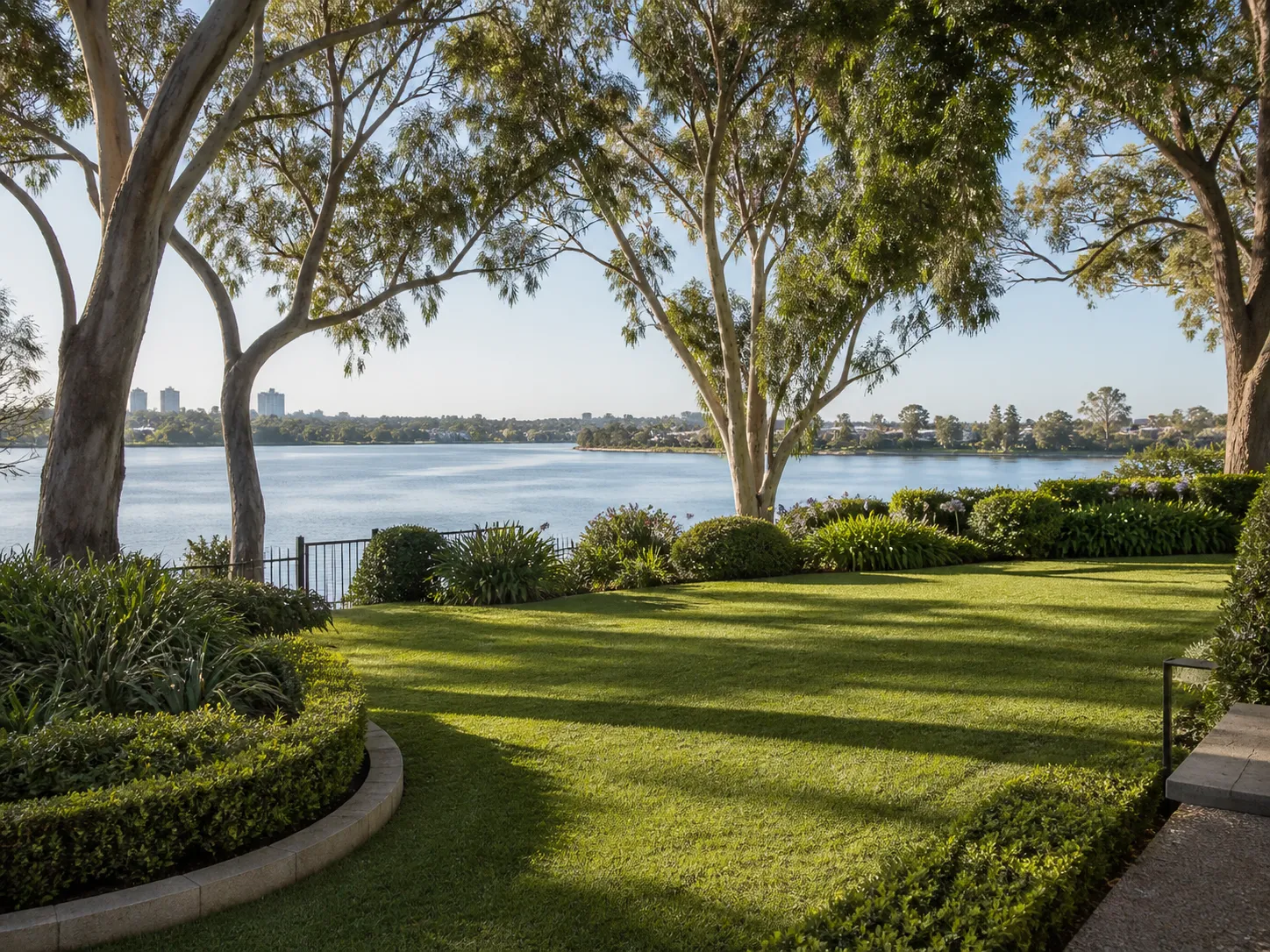 A river-facing garden in Perth's south-of-the-river suburbs with established trees and lawn.